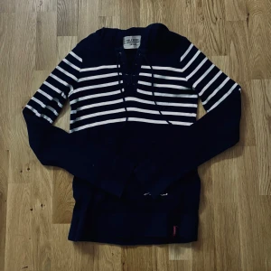 Marinblå och vit randig hoodie från Hilfiger - Säljer en marinblå hoodie med vita ränder från Holebrook. Tröjan har huva med snörning och långa ärmar. Perfekt för en avslappnad stil och passar bra till jeans eller shorts. Bra passform och perfekt för en sommarkväll.