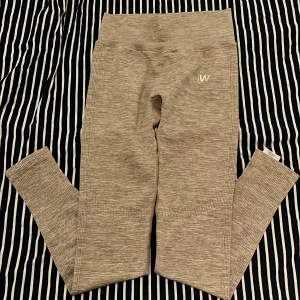 Grå/beige träningsbyxor från ICANIWILL - Säljer ett par grå/beigefärgade sömlösa träningsbyxor från ICANIWILL. De har hög midja och ribbade detaljer längs benen och midjan. Perfekta för träning och riktigt sköna att ha på sig. Snygg logga framtill. Är aldrig använda men har tyvärr inte orginalförpackningen kvar.