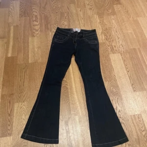  bootcut jeans - Snygga svarta bootcut jeans med klassisk femficksdesign. De har en lågmidjad passform och är perfekta för en avslappnad stil. Jeansen har en dragkedja och knapp framtill. Mörkblå färg. 