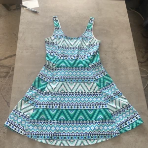 Mönstrad klänning från H&M Divided - Säljer en färgglad klänning från H&M Divided med ett geometriskt mönster i blått, grönt och vitt. Klänningen har breda axelband och en rund halsringning. Perfekt för en somrig look! 🌞
