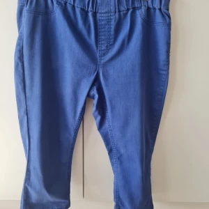 Capri byxor från KappAhl - Snygga blå Capri byxor från KappAhl med elastisk midja för extra komfort. Byxorna har en rak passform och två bakfickor. Storlek 46. Kan hämtas i Vallentuna.