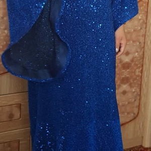 Blå glittrig långklänning - Säljer en blå långklänning med glitter och långa ärmar. Klänningen har en rund halsringning och är täckt av glittriga paljetter som ger en festlig look. Perfekt för speciella tillfällen när du vill sticka ut.
