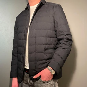 Svart quiltad jacka från Massimo Dutti - Säljer en stilren svart quiltad jacka från Massimo Dutti. Jackan har lång ärm, dragkedja och knappar framtill samt två fickor med lock. Perfekt för kyligare dagar och passar till många olika outfits.