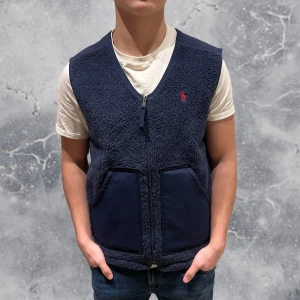 Ralph Lauren Fleece Väst Navy Blå - •Ralph Lauren Fleece Väst Navy Blå. Skick: 9/10, Inga skador & fåtal gånger använd! Storlek: XS Herr. Modell: 173 cm, 65 kg. Passar bra på modellen! Authentic: ✅, QR Kod finns även i plagget. Hör av dig vid frågor eller funderingar, mvh Hessler’s;)