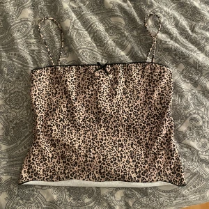 Leopardmönstrad linnetopp från Bershka - Säljer en snygg leopardmönstrad linnetopp från Bershka. Toppen har smala axelband och en liten rosett framtill. Perfekt för en trendig look!