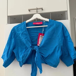 Blå croppad linnetopp  - Säljer en snygg blå croppad linnetopp från JJXX. Toppen har en knytning framtill och trekvartsärmar, perfekt för en somrig look.