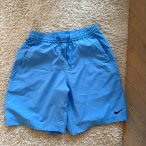 Nike shorts - Säljer ett par ljusblå träningsshorts från Nike, perfekt nu till sommaren för träning, promenader eller bara en stund ute i solen, storlek S men passar mig som är 183, tveka inte vid intresse eller funderingar! Nypris var 599kr på Stadium