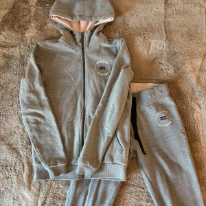 Grå hoodie och byxor från Sebago - Säljer en grå hoodie med matchande byxor från Sebago. Hoodien är aldrig använd och byxorna är använda några gånger men har inga defekter förutom på sebago-märket på högersidan. Ett väldigt skönt och lyxigt mjukisset💕utsprungspris ca 2000kr