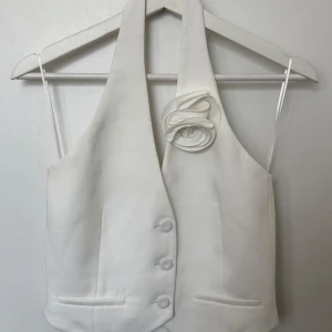 Vit halterneck väst med blomdetalj - Vit kostymväst från Mango med en fin detalj. I mycket bra skick. I storlek S. 