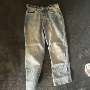 Lucid Club Outer ljusgrå denimbyxor - Unika ljusgrå denimbyxor från Lucid Club Outer med coolt tryck på bakfickan och textdetaljer. Byxorna har rak passform, klassisk femficksdesign och är tillverkade i 100% bomull. Perfekta för dig som vill sticka ut med streetstyle-vibe.