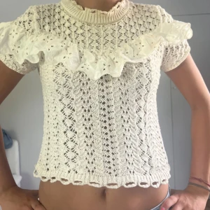 Vit stickad blus med volang - Supersöt vit stickad blus med korta ärmar och broderad volang över bröstet💕superfin men säljer pågrund av att den är för liten❤️ Fråga för fler bilder