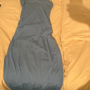 Ljusblå långklänning med smala axelband - Säljer en stilren ljusblå långklänning med smala axelband. Klänningen har en enkel och elegant design, perfekt för dig som gillar minimalistisk stil. Materialet känns mjukt och följsamt mot kroppen.