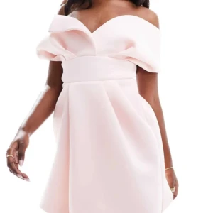 Volang klänning - Superfin ljusrosa kortklänning med offshoulder och voluminösa ärmar. Klänningen har en markerad midja och vidd i kjolen, vilket ger en elegant och modern siluett. Perfekt för dig som vill sticka ut med en romantisk och trendig look.