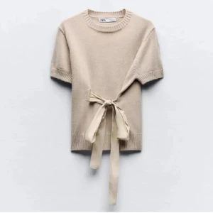 Beige stickad tröja med knyt från Zara - Superfin beige stickad tröja från Zara med korta ärmar och snygg knytning i midjan. Perfekt för dig som gillar en enkel men ändå unik look. Tröjan har ribbade detaljer vid hals, ärmslut och nederkant.skickar bara om du följer mig💞