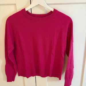 Ceriserosa tröja från mango - En ceriserosa tröja från mango med rund halsringning och långa ärmar. Tröjan har en enkel, clean design med ribbade muddar vid ärmslut och nederkant. Perfekt för dig som gillar färg och vill ha en basic men snygg tröja i garderoben.