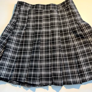 Svartvit rutig plisserad kortkjol - Svart och vit rutig kortkjol med plisserad design från Yesstyle. Kjolen är fodrad och har inre safety shorts. Använd ett fåtal gånger. 