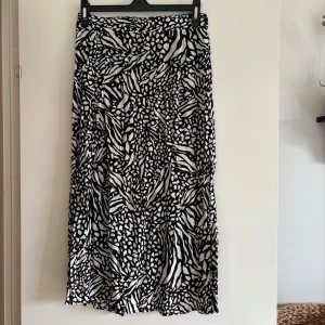 Svartvit långkjol med zebramönster - Snygg svartvit långkjol med coolt zebramönster. Kjolen har en rak och flowy passform som ger en avslappnad vibe.