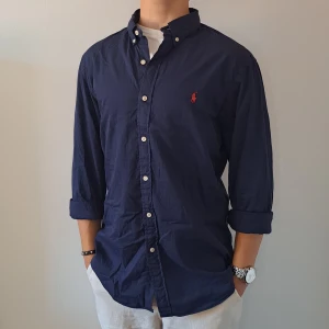 Marinblå Ralph Lauren Skjorta - Stl L, Slim Fit - Hej säljer en fin Ralph Lauren skjorta I färgen Marinblå, Perfekt till sommaren! 🏖🏝 | Skick: 8,5/10 | Stl: L, Slim fit | Han på bilden är 172cm, men passar längre | Fraktar spårbart med Instabox eller Postnord | Mvh Galgen 🤗