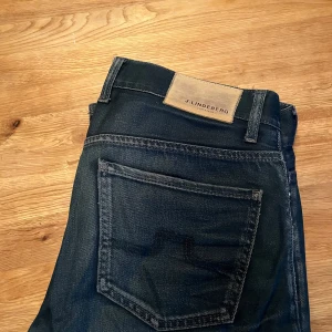 Mörkblå jeans från J.Lindeberg - Snygga mörkblå jeans från J.Lindeberg med klassisk femficksdesign och diskret logga på bakfickan. Passform: Slim | Skick: Bra | Storlek: W33 L34 | Hör av dig om du har frågor!!!