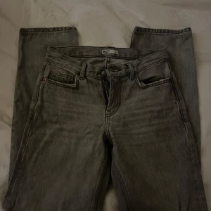Grå Gina straight jeans - Säljer ett par ljusgråa jeans med rak passform. Jeansen har fem fickor, bälteshällor och knappgylf. De är tillverkade i robust denim och har en tidlös look som funkar till allt. Perfekta för dig som gillar vintagevibbar och enkel stil.