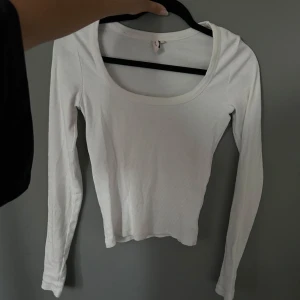 Vit ribbad långärmad topp - En basic vit långärmad topp med rund, djup ringning och ribbad struktur.