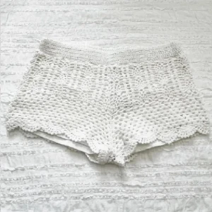 Vita virkade shorts med volangkant - Superfina vita virkade shorts med hög midja och söt volangkant. Perfekta till stranden eller festivalen! Luftigt material och snygg passform som ger en chill sommarvibe.