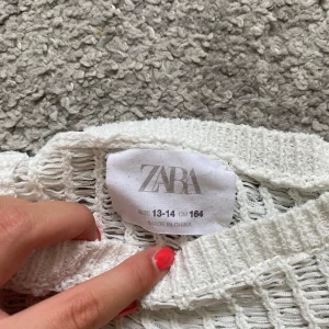 Vit stickad tröja från Zara - Vit stickad tröja från Zara i storlek 164. Tröjan har ett luftigt, öppet stickat mönster och är croppad med långa ärmar och ribbade muddar. Perfekt för lager-på-lager och en chill, trendig look.