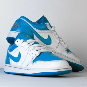 Nike Air Jordan 1 Low blå/vit - Nike Air Jordan 1 Low sneakers i fräsch blå och vit färg. Dessa perfekta Jordans  är restaurerade för att upplevas som nya!  Nypris: 1500:-  OBS: Bilderna är tagna av oss (Green Sneaks). Det är exakt detta par du får i detta skick!
