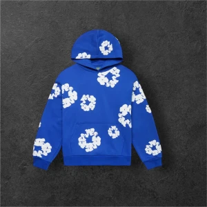 Denim tears set, Blå hoodie och blå mjukisbyxor med vita blommor - Säljer en Denim tears set med stora vita blommönster över hela sätet. Hoodien har huva, magficka och långa ärmar. Byxorna har fickor, den har också band, så det går och spänna till. Perfekt för dig som gillar streetwear och vill sticka ut med en färgglad och unik stil.