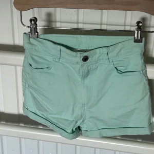 2-pack shorts från H&M, stl 140 - Två par klassiska shorts från H&M i storlek 140. Ena paret är mintgröna och det andra är svarta. Båda har uppvikta benslut, femficksmodell och knapp med dragkedja. Perfekta för varma dagar och enkel att matcha med allt.