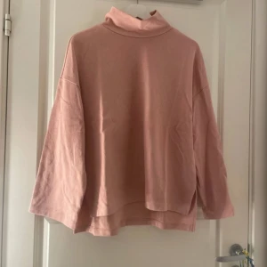 Ljusrosa polotröja med loose fit - Enkel och snygg ljusrosa polotröja med lös passform och långa ärmar. Tröjan har hög krage och är tillverkad i mjuk bomull, perfekt för lager-på-lager. Passar dig som gillar en chill och avslappnad stil.