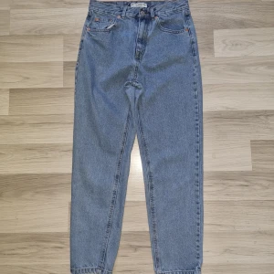 Blå jeans från Pull&Bear, hög midja - Klassiska blå jeans från Pull&Bear i modell med hög midja och raka ben. Jeansen har fem fickor, gylf med dragkedja och knapp, samt snygga kontrastsömmar. Perfekta för en avslappnad och trendig look.