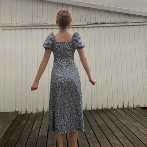 Blommig blå långklänning med puffärm - En super fin blå långklänning i ett skönt luftigt tyg! Super fin som både en festklänning eller en strandklänning