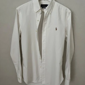 Vit Ralph Lauren Skjorta - Strl S, Slim Fit - Hej säljer nu min fina Ralph Lauren skjorta i storlek S och den sjukt populära modellen Slim Fit. Den är i nyskick och kommer vara otroligt snygg på sommaren. Nypris cirka 1600kr! Vid frågor eller fundering tveka inte på att höra av dig! 🌊🍾