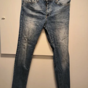 Blå slim fit jeans med slitningar - Snygga blå jeans med slim fit-passform och lätt slitna detaljer på framsidan. Klassisk femficksmodell med dragkedja och knapp. Jeansen har en något ljusare tvätt och raka bakfickor. Perfekta för en avslappnad streetstil. Storlek 31/32