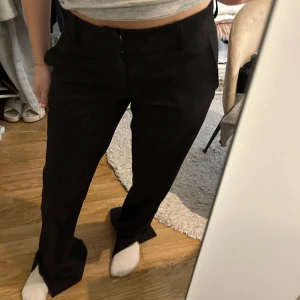 Svarta lågmidjade kostymbyxor - Snygga svarta kostymbyxor med låg midja och slits längst ner. Passar till allt 💗 Från BikBok i storlek 36! Lite slitna i ena sömmen längst ner, dock inget som syns