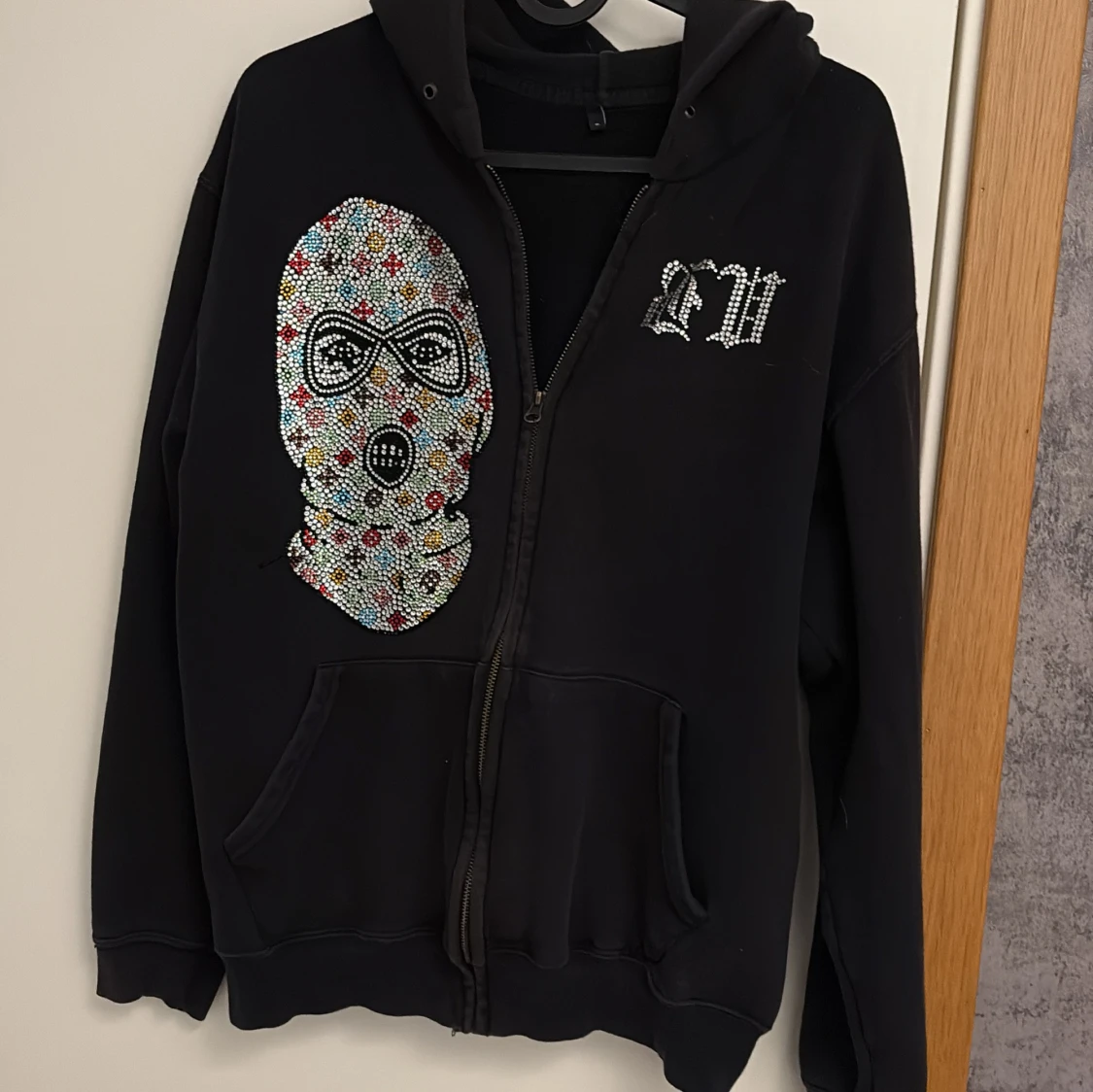 Svart hoodie med strassmask och text