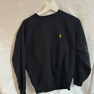 Svart Polar sweatshirt XS - Svart sweatshirt från Polar med en gul broderad logga på bröstet. 