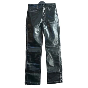 Svarta glansiga byxor med raka ben - Säljer ett par svarta glansiga ”lack”  byxor med raka ben och vita kontrastsömmar. 