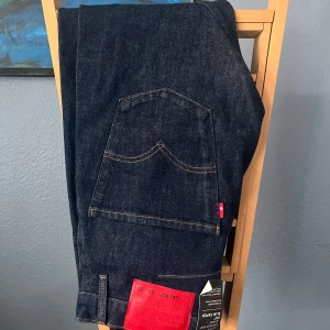 Helt Nya Levi's 512 Slim Taper Jeans, Butikspris: 1399kr - Mörkblå Levi's 512 jeans med slim taper passform. Storlek 30x32. Klassisk femficksdesign, röda Levi's-taggen på bakfickan och röd patch bak. Jeansen är tillverkade i denim och har snygga kopparfärgade nitar och knappar. Butikspriset är 1399kr. 