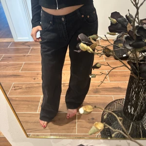 Svarta jeansbyxor med rak passform - Säljer ett par svarta jeansbyxor med normal passform och raka ben. Klassisk femficksmodell med knapp och dragkedja framtill. Perfekta till en avslappnad stil och enkla att matcha med olika toppar.