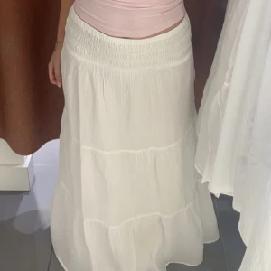 Vit långkjol med resår i midjan - Säljer en flowy vit långkjol med bred resår i midjan. Kjolen har en luftig och lätt känsla, perfekt för varma dagar. Enkel och stilren design som passar till många olika toppar. Är från barnavdelningen i storlek 15/164 men motsvarar en xs