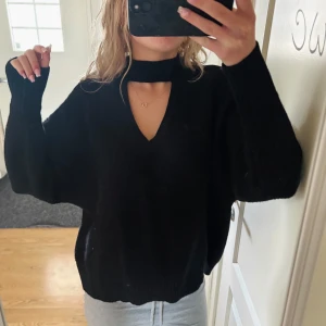 Svart stickad tröja - Säljer en svart stickad tröja med v-ringning och detalj i halsen. Oversized passform som är både trendig och bekväm. Perfekt att styla till jeans eller kjol.