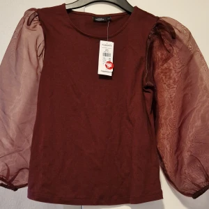 Vinröd topp med puffärmar från KappAhl - Säljer en vinröd topp från KappAhl med transparenta puffärmar i mesh. Toppen har rund halsringning och är i ett mjukt material. Perfekt för dig som vill ha något unikt och trendigt i garderoben! Köpte 50% av rea,säljer 85 kr, jag har 2 stycken. 
