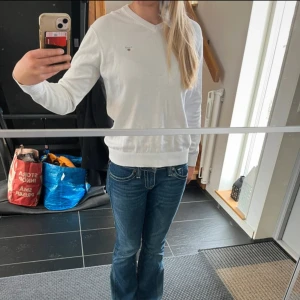 Vit v-ringad tröja från Gant - Säljer en klassisk vit v-ringad tröja från Gant i bomull. Tröjan har långa ärmar, ribbade muddar och liten broderad logga på bröstet. 