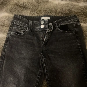 Svarta jeansbyxor från Gina Tricot - Säljer ett par svarta jeansbyxor från Gina Tricot med hög midja och raka ben. Byxorna har två knappar och dragkedja framtill samt fickor både fram och bak. Perfekta till din vardagsstil!