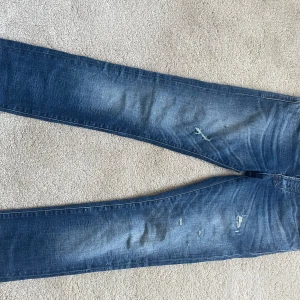 Blå slim jeans från Jack & Jones - Säljer ett par blå slim fit jeans från Jack & Jones, modell SLIM GLENN. Jeansen har lätt slitna detaljer det är storlek 28/32   KAN MÖTAS I STAN VID SNABB AFFÄR