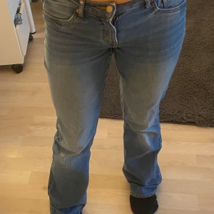 Blå bootcut jeans - Säljer ett par klassiska blå bootcut jeans med normal passform. Jeansen har fem fickor, dragkedja och knapp framtill. De är tillverkade i denim och har en lätt tvättad look med ljusare partier framtill och baktill.