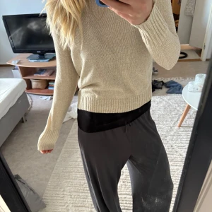 Beige stickad tröja - Säljer en stilren beige stickad tröja med rund halsringning och långa ärmar. Tröjan har en klassisk passform och ribbade muddar vid ärmslut och nederkant. Perfekt för lager-på-lager och enkel att matcha med olika outfits.