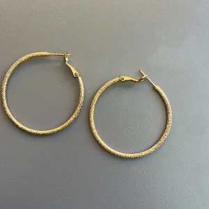 Guldiga creoler örhängen - Stora, runda creoler i guldton med glittrig yta.  Lätta att bära, unte tubga för öronen.